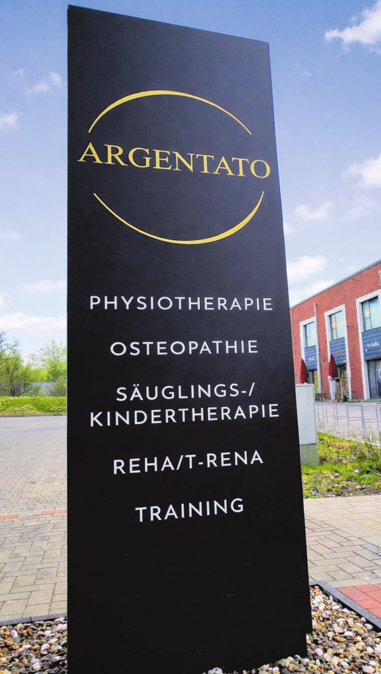 Die Stele vor dem Gebäude weist auf das umfassende Therapie- und Trainingsangebot hin.