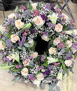 Ein Blütentraum aus Rosen, Staticen, Glockenblumen, Allium, Eustoma, Astilben, weißen Lilien und Wicken ist dieser Kranz.