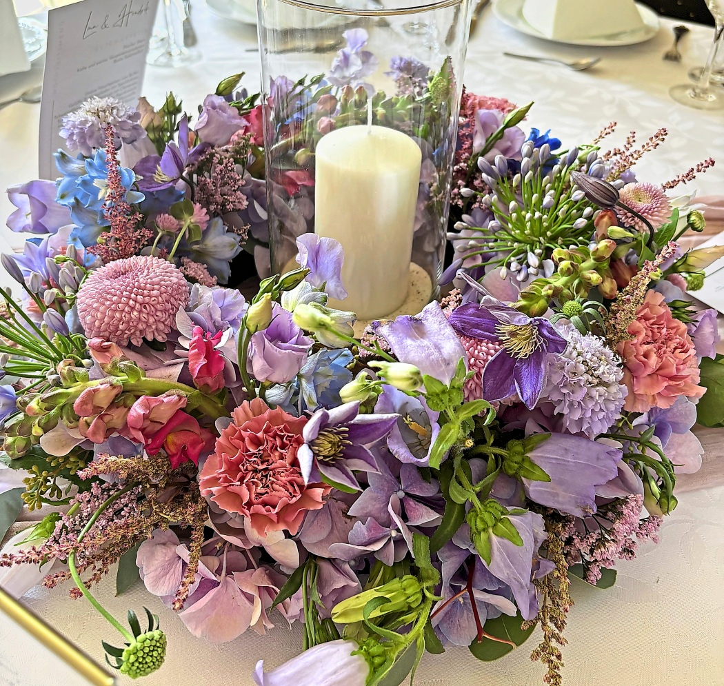 Eine Tischdekoration mit frischen Sommerblumen und stimmungsvollem Kerzenlicht.