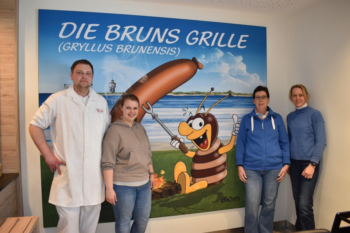 Von links: Juniorchef Sören Mannott, seine Lebensgefährtin Nina Janssen, Inhaberin Hedda Bruns-Mannott und die stellvertretende Geschäftsführerin Erika Ziemann vor dem neuen Wandbild, das vom Esenser Künstler „Hösti“ gestaltet wurde. Hier drauf ist die „Bruns-Grille“ zu sehen, für die im Rahmen eines Gewinnspiels noch ein passender Name gesucht wird. BILDER: Frank Brüling