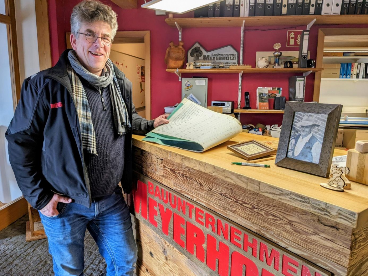 Bauingenieur Ulf Meyerholz führt das Familienunternehmen in 3. Generation. Hier ist er mit einem Foto seines Großvaters und Firmengründers Karl-Heinz Meyerholz sowie mit einem Rechnungsbuch aus dem Gründungsjahr 1956 zu sehen. BILD: Walburg Dittrich