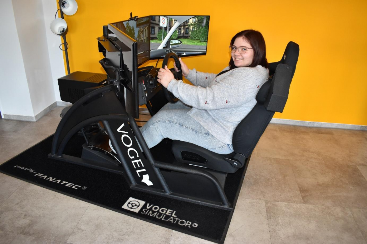Meike Bents von der Fahrschule Hüske lädt dazu ein, den Fahrsimulator zu testen. Bild: Frank Brüling