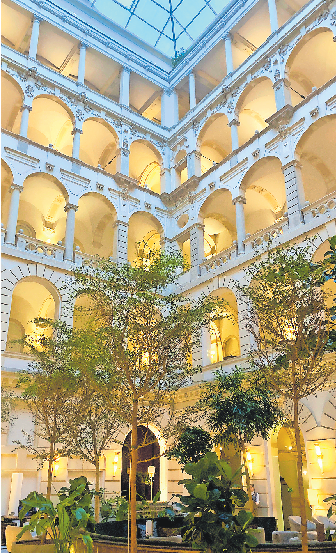 ZUR BLAUEN STUNDE ERHELLEN ZAHLREICHE LEUCHTEN DIE ARKADENGÄNGE DES OPULENTEN ATRIUMS MIT DER LOBBY IM ERDGESCHOSS. DER EINST OFFENE INNENHOF WURDE MIT EINER GLÄSERNEN PYRAMIDE GEDECKT.