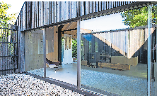 BLICK VOM PATIO IN DEN WOHNRAUM MIT SPIEGELUNG EINES KUNSTWERKS.