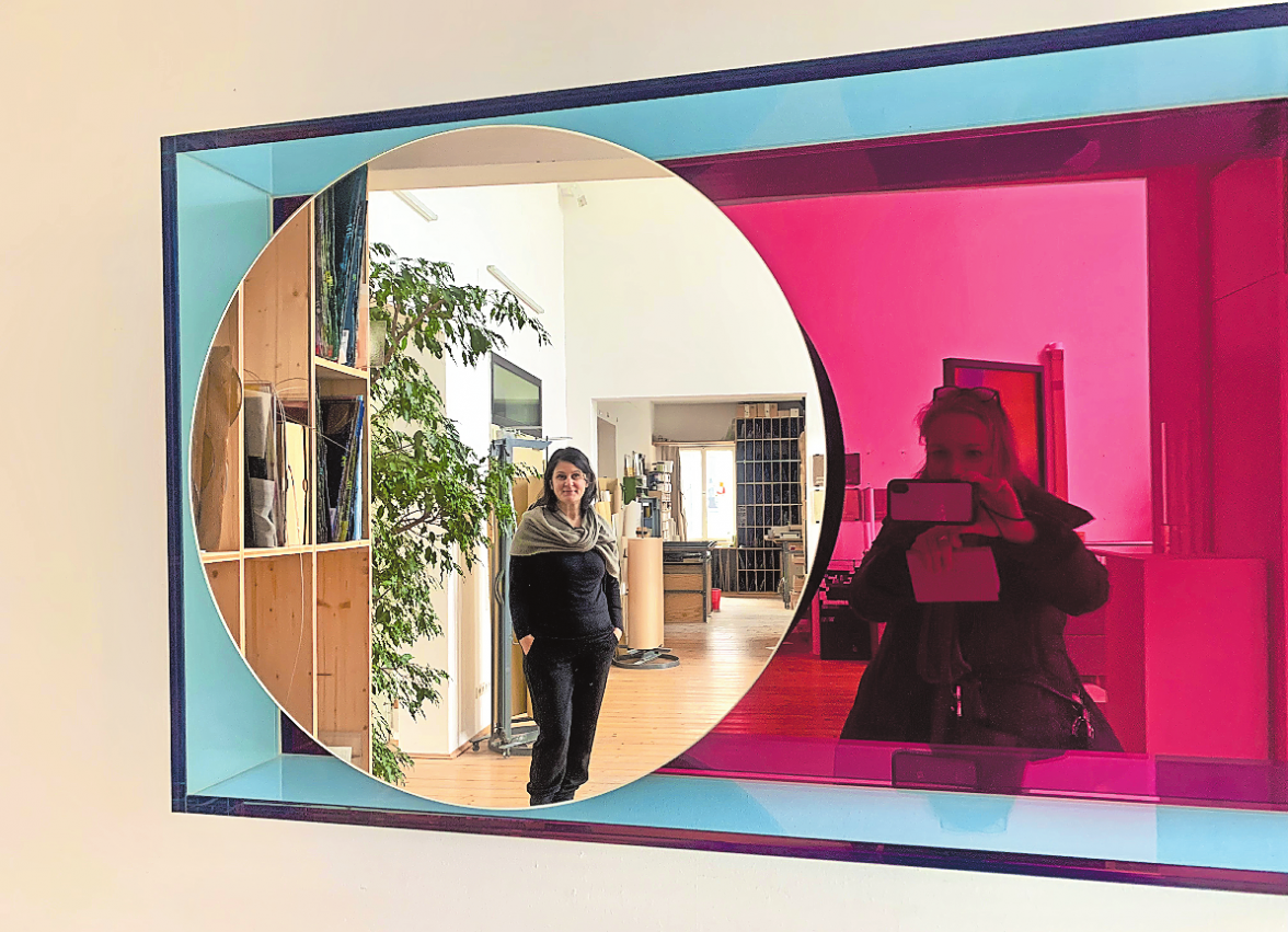 GESCHÄFTSFÜHRERIN KATJA ZUKIC IM FOKUS VON WANDSPIEGEL ,KROMO“ DES DESIGNERS KARIM RASHID - LAMINIERTE FARBIGE SPIEGEL UND POLIERTES ALUMINIUM. EIN UNIKAT, DAS REPRODUZIERT WERDEN KANN. FOTO: FRANZISKA HORN