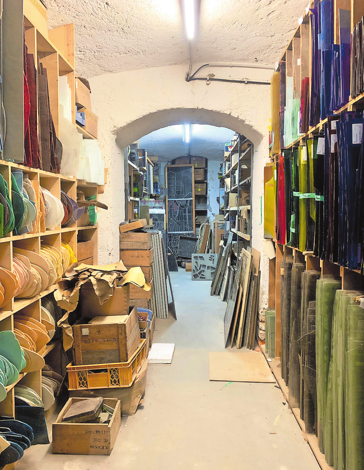IM KELLER-ARCHIV DER WERKSTATT FINDEN SICH REGALE VOLLER VIELFARBIGER PIASTRE, DIE IN VENEDIG GEBRANNT WERDEN VON DER FORM HER PIZZABÖDEN ÄHNELN. AUS IHNEN ENTSTEHEN GROSSFORMATIGE KUNSTWERKE. FOTO: FRANZISKA HORN