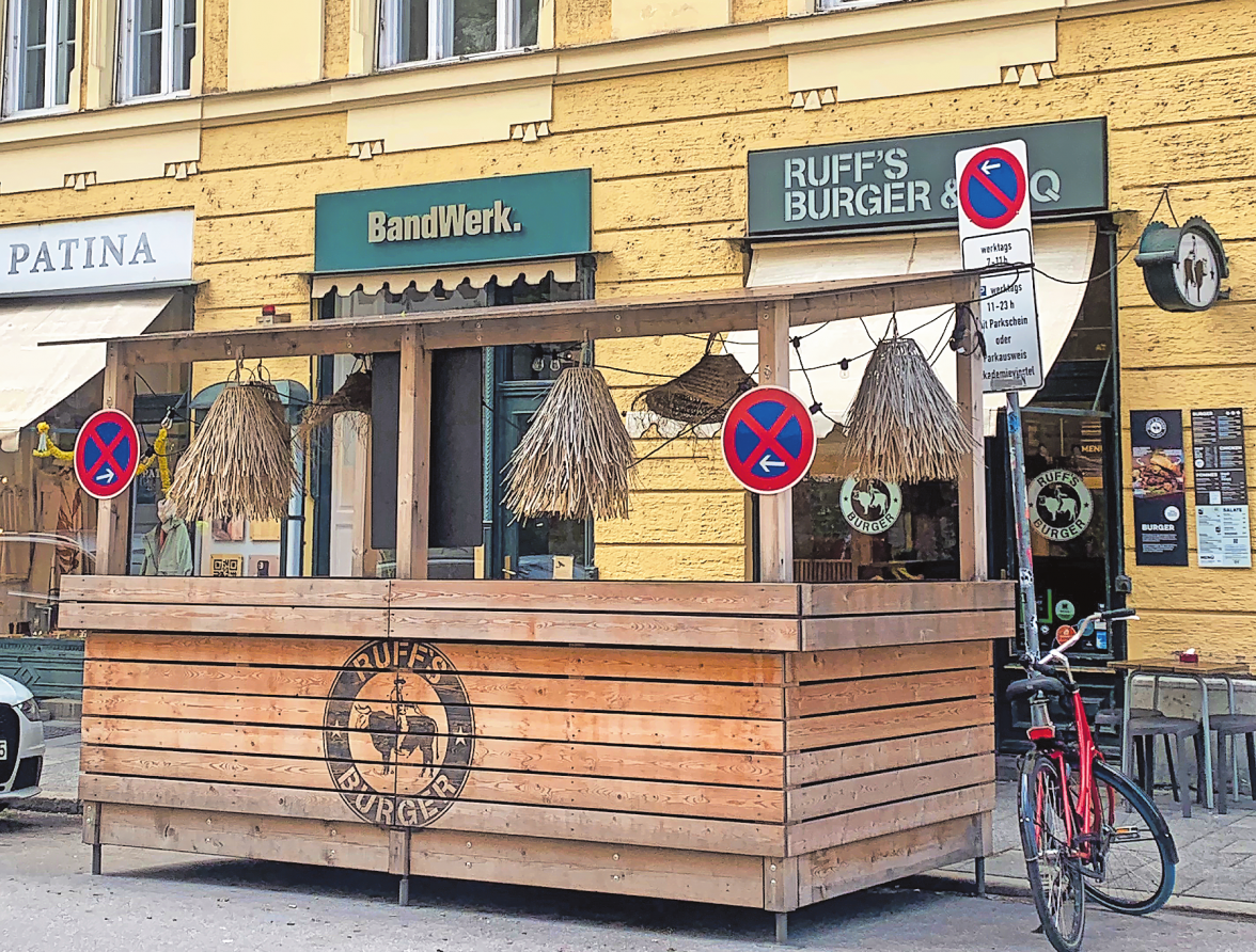 DA BEKOMMT „AUF DER STRASSE SITZEN“ EINE NEUE BEDEUTUNG: DIESE HÖLZERNE MINI-ARCHITEKTUR IN DER TÜRKENSTRASSE GLEICHT EINEM AUF BODENLEVEL VERANKERTEN BALKON.