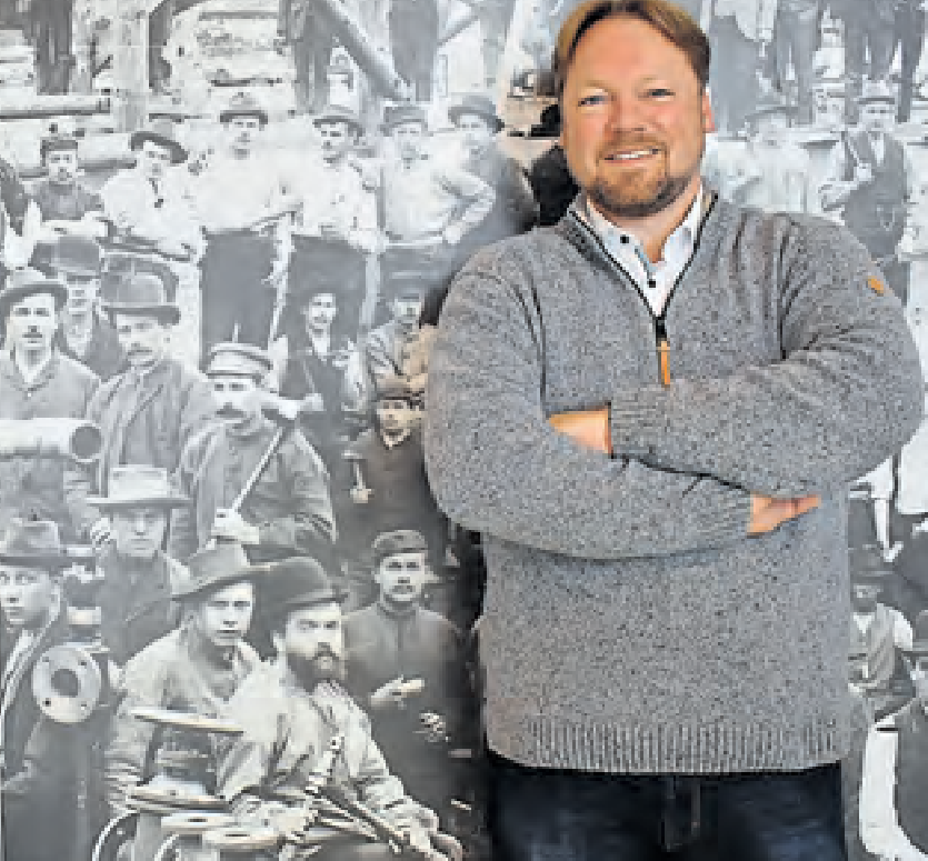 Oliver Kumbartzky, FDP-Landesvorsitzender und Landtagsabgeordneter, vor einer Fotowand, die Kanalarbeiter zeigt. Sein Ururgroßvater Wilhelm Kumbartzky half beim Schleusenbau in Brunsbüttel mit. FOTO: STEFAN LIPSKY