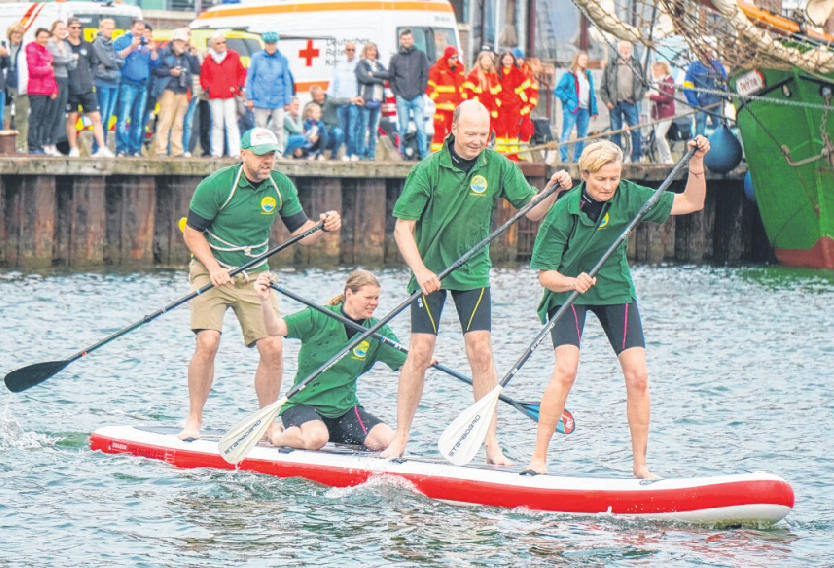 Stand-up Paddling-Rennen. Von der Hafenkante aus können die jubelnden Fans ihre Favoriten anfeuern.