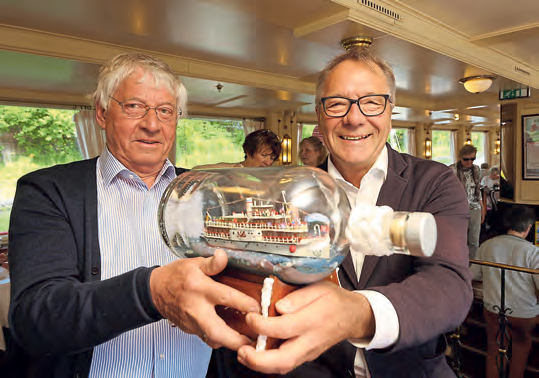 Das hat es auf der „Freya“ noch nicht gegeben - ein vollbeleuchtetes „Freya“-Buddelschiff mit Positionslaternen und allem Schnickschnack hat Reeder Sven Paulsen (rechts) in Empfang genommen. Der ehemalige Elektromechaniker Karl Heinz Böhe von Arnstedt (73) von Nordstrand hat die Miniatur in 250 Stunden gebaut. Die bauchige Buddel hat er einem Kieler Großhändler abgeschnackt und in ein Kunstwerk verwandelt. Die kleine „Freya“ fährt von nun an auf dem Original täglich auf dem Nord-Ostsee-Kanal spazieren. FOTO: MICHAEL STAUDT
