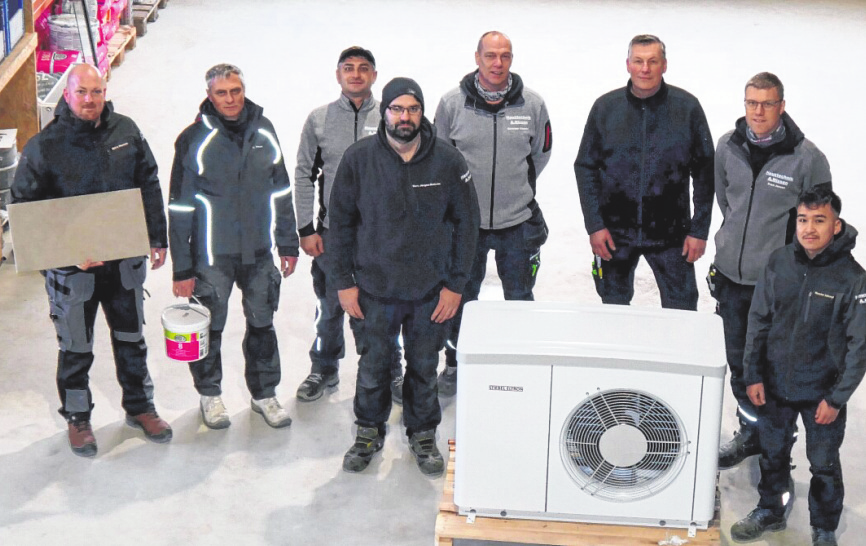Björn Hansen, Eddi Sippel, Georg Kühn, Marc Jürgen-Knierim, Christian Clausen, Sven Pankratz, Sven Jessen und Auszubildender Nasim Ishaqi (v.l.) beim Verladen einer Wärmepumpe.
