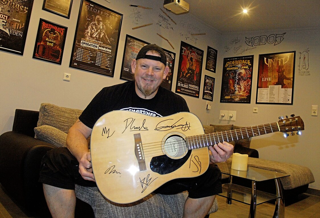 Im Backstage-Bereich des Hademarscher Hofs: Frank Olschewski mit einer Gitarre, die Ex-„Queensryche“-Sänger Geoff Tate und dessen Bandkollegen signiert haben. Foto: Hans-Jürgen Kühl