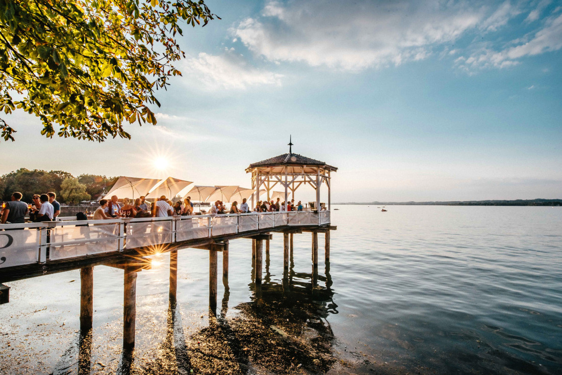 Die Bodenseeperle Bregenz weiß mit vielen magischen Momenten zu begeistern. Ein Sundowner mit Südsee-Flair lässt sich am besten auf der über dem See schwebenden Fischersteg-Sunset Bar genießen. Foto: epr/visitbregenz/Christiane Setz
