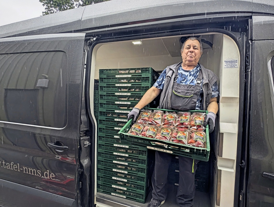 Sergej Bachmann hat gerettete Lebensmittel abgeholt und trägt sie aus dem Transporter.