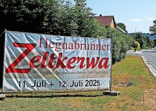 Mit einem großen Werbebanner weisen die „Hegnabrunner Moggerla“ am Ortseingang auf ihre Zeltkerwa hin.