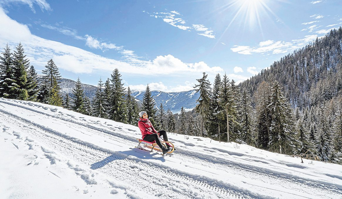 Kindliche Freude neu entdeckt: Rodeln mit Blick auf die Nockberge - so fühlt sich Winterglück an. Foto: Mathias Prägant