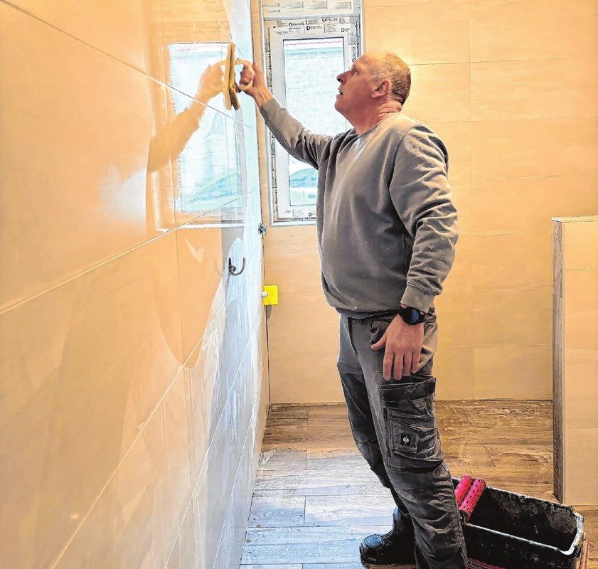 Das Bad ist gefliest. Hanjo Kolm reinigt die Wand. Im März sollen die neuen Mieter in die fertige Wohnung einziehen.