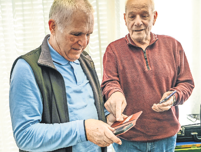 Wolfgang Baumann (links) und Walter Fischer lösen ein Handy-Problem.