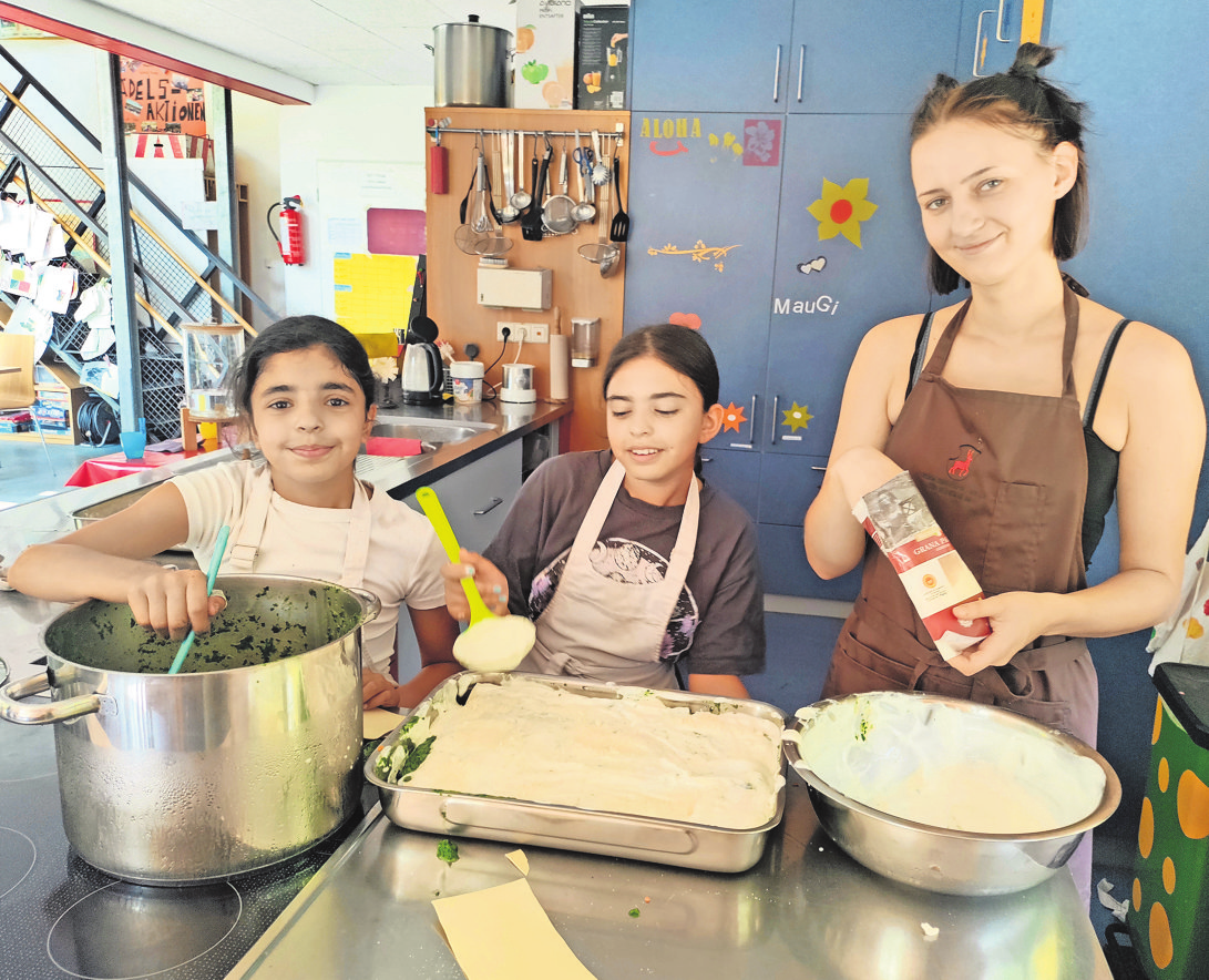 Simay (links) und ihre Schwester Burcu gehen Ferienhelferin Oxana zur Hand. Zum Mittagessen gibt es leckere Spinat-Lasagne im Mauga Nescht. Fotos: Martina Fürstenberger