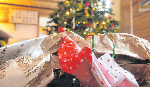 Geschenkpapier liegt auf dem Boden vor einem Weihnachtsbaum. Foto: dpa/Karl-Josef Hildenbrand