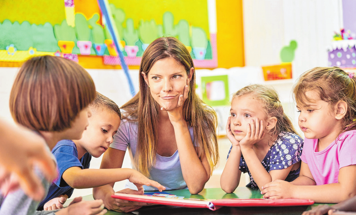 Erzieherin und Kinder lesen und spielen zusammen im Kindergarten. Foto: Robert Kneschke/www.adobe.stock.com