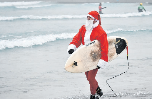 Surfen im Weihnachtsmann-Outfit? Das ist in Australien durchaus üblich. Foto: Ben Birchall/PA Wire/dpa