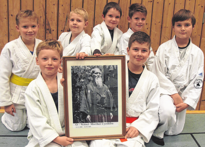 Jugendliche MTSV-Aikidoka mit einem Foto des Aikido-Begründers Morihei Ueshiba.