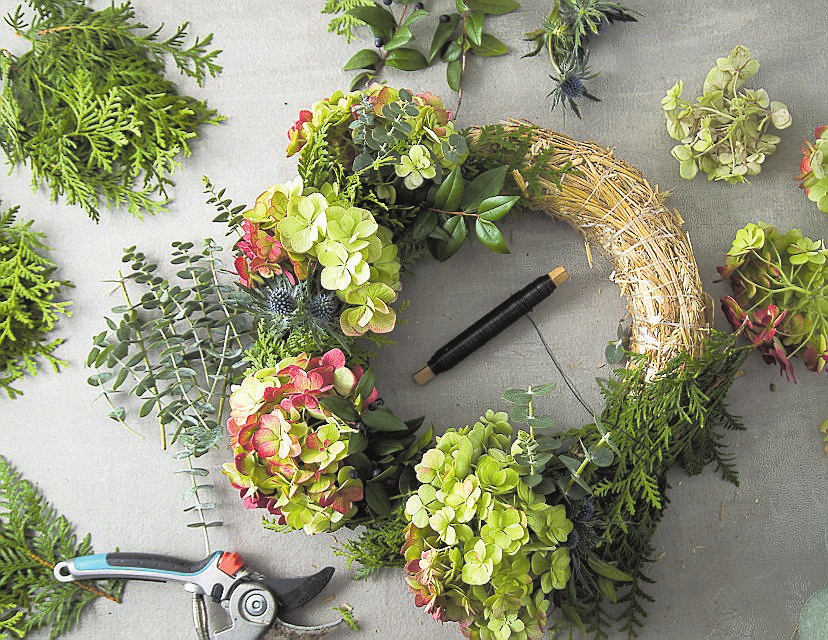 Die grüne Grundlage wird gegen den Uhrzeigersinn angebracht. Dann kommen dekorative Blüten und Samenstände, etwa von Hortensie und Edeldistel. FOTO CHRISTIN KLOSE/DPA
