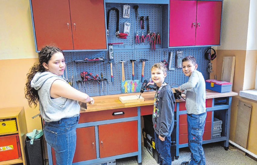 Mia Rosa, Finn und Logan (v.l.n.r.) freuen sich über die Werkbank in der Lebuser Burgschule. Sie ist eine Spende von Dana Harth. Foto: Hauskrankenpflege Herzenssache