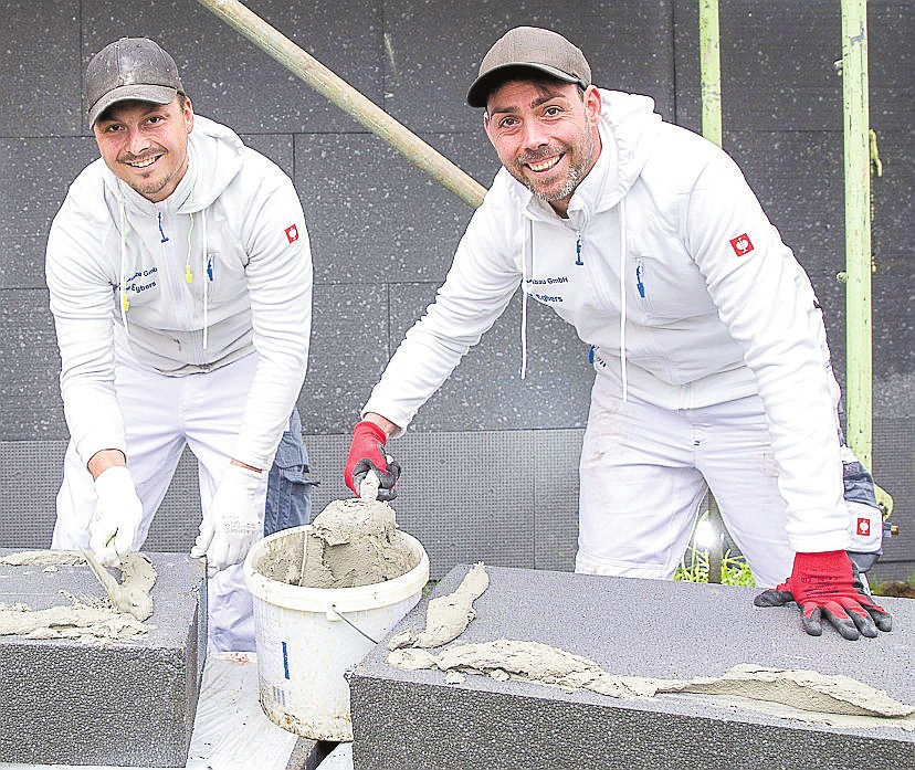 Rene Egbers (1.) und sein Bruder Manuel Egbers bringen Armierungskleber auf zwei Dämmplatten eines Wärmedämmverbundsystems auf.