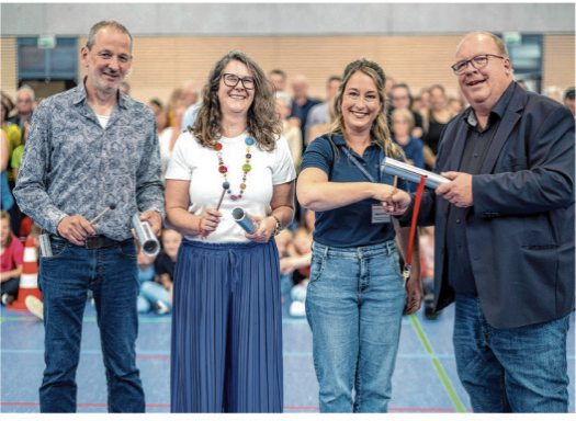 Die Architekten vom Büro Hartmaier + Partner, Tilman Eder (I.), Anja Gaub (2.v.l.), Jochen Schmid (r.) sowie Tanja Gröning, die Bereichsleiterin der Klassen 5 und 6, bei der Schlüsselübergabe am 15. Juni. Foto: PR