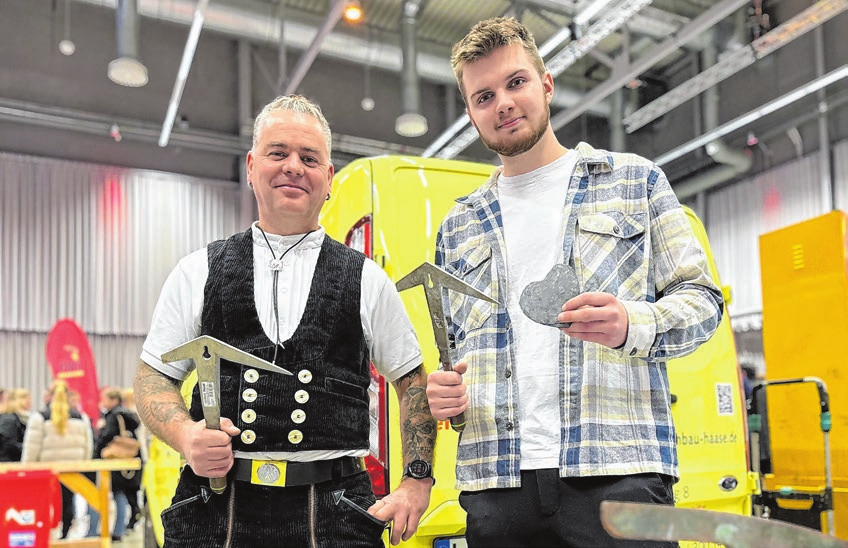 e Dachdeckermeister René Haase und Marc Schöler aus - Frankfurt mit einem Dachstein aus Schiefer und in Herz- form auf der Mitmachmesse im vergangenen Jahr