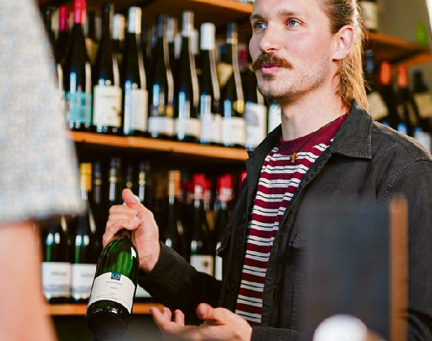 Mit geübtem Blick wird die passende Flasche aus dem sorgfältig kuratierten Weinsortiment ausgewählt. Foto: Genusszimmer