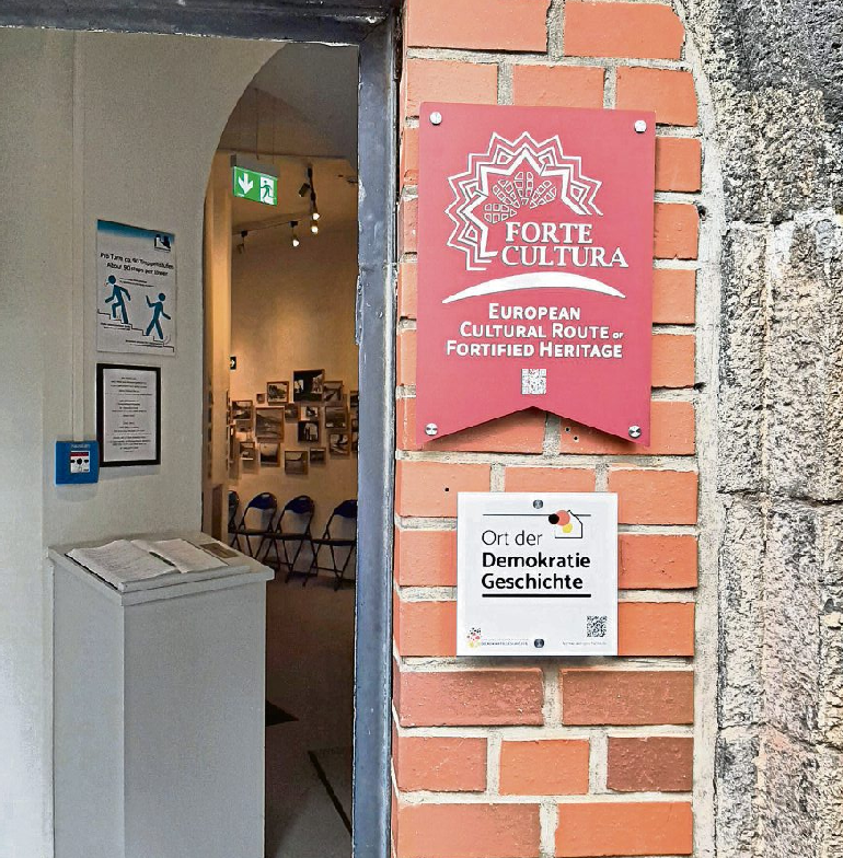 Am Eingang des Friedensmuseums weisen Tafeln auf die Einbindung in die Kulturroute Forte Cultura und die „Orte der Demokratiegeschichte“ hin. Foto: Volker Thehos