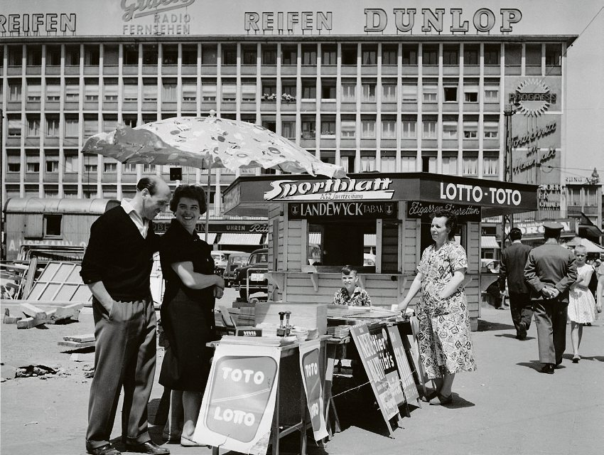 Die gleiche Annahmestelle ein paar Jahre später. Am Bauwagen im Hintergrund, sieht man, dass der Wiederaufbau voranschreitet. Der Kiosk musste einem Kaufhaus weichen und zog um.