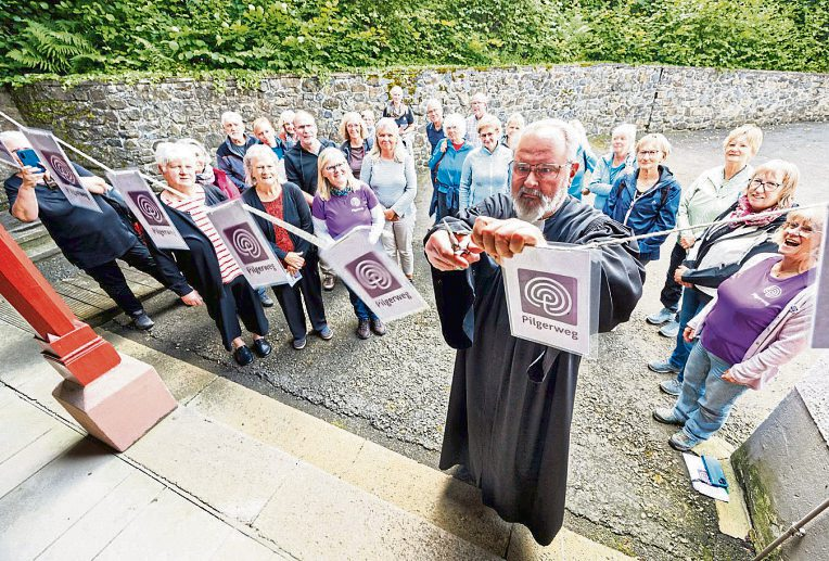 Dekan Axel Wengenroth eröffnet den neuen Pilgerweg offiziell und durchtrennt im Beisein der Gäste das symbolische Band.