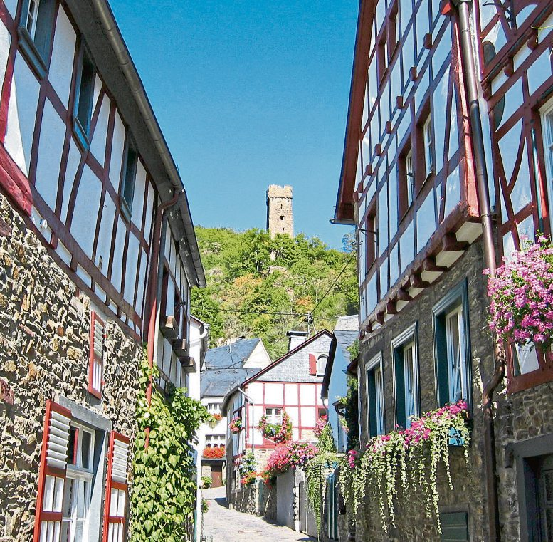 Fachwerk und Blumenschmuck in Monreal, darüber erhebt sich die Ruine der Philippsburg. Foto: Ingo Becker / Touristik-Büro Vordereifel