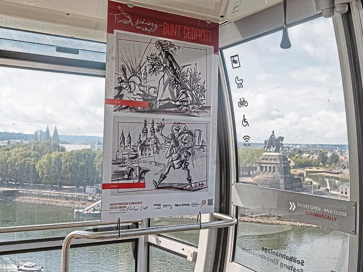 Kunst mit Aussicht: In den Gondeln der Koblenzer Seilbahn sind unter dem Titel „Schwarz-weiß ... bunt gedacht“ Karikaturen des Künstlers Philipp Dott zu sehen. Foto: Rainer Claaẞen