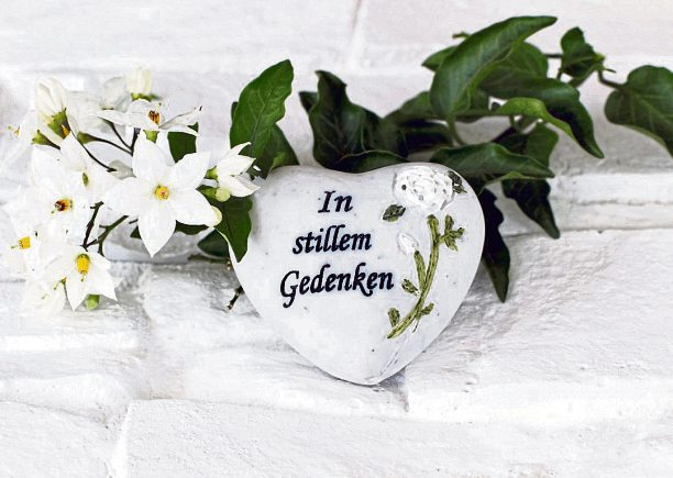 Ein persönliches Zeichen der Erinnerung: Blumen und ein Gedenkherz können bei einer Trauerfeier einen stillen Akzent setzen. Foto: Racamani - stock.adobe.com