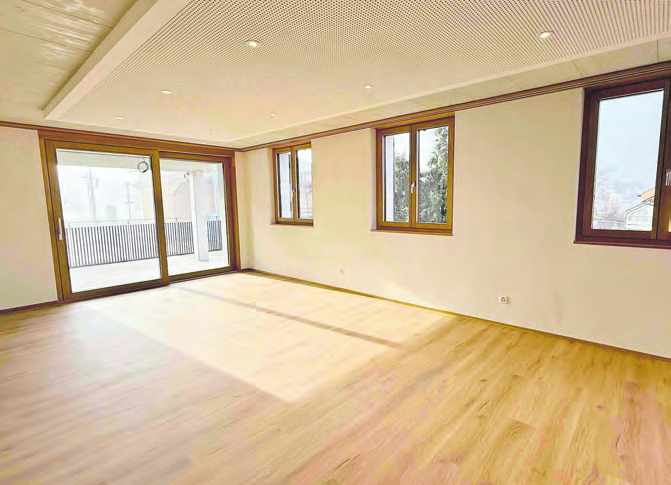 Offenes Wohn-Esszimmer mit Akustikdecke und Direktzugang zum Balkon.